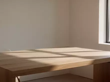 Ein minimalistischer, lichtdurchfluteter Raum mit einem leeren Holztisch in einer ruhigen, privaten Atmosphäre. - Foto: über boerse-global.de