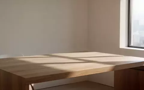 Ein minimalistischer, lichtdurchfluteter Raum mit einem leeren Holztisch in einer ruhigen, privaten Atmosphäre. - Foto: über boerse-global.de