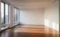 Ein leeres, modernes Büro mit weißen Wänden und großen Fenstern, das Tageslicht wirft weiche Schatten auf den Holzboden. - Foto: über boerse-global.de