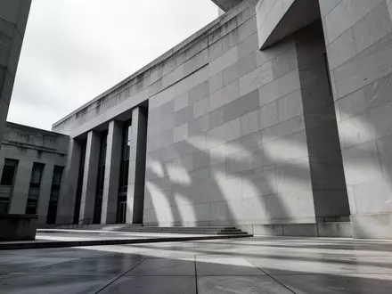 Die Fassade eines modernen Gerichtsgebäudes aus grauem Stein bei bewölktem Himmel. - Foto: über boerse-global.de