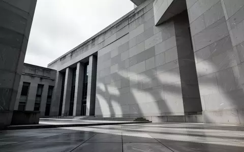 Die Fassade eines modernen Gerichtsgebäudes aus grauem Stein bei bewölktem Himmel. - Foto: über boerse-global.de
