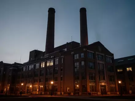 Ein großes, historisches Kraftwerksgebäude auf einem Universitätsgelände in der Abenddämmerung. - Foto: über boerse-global.de