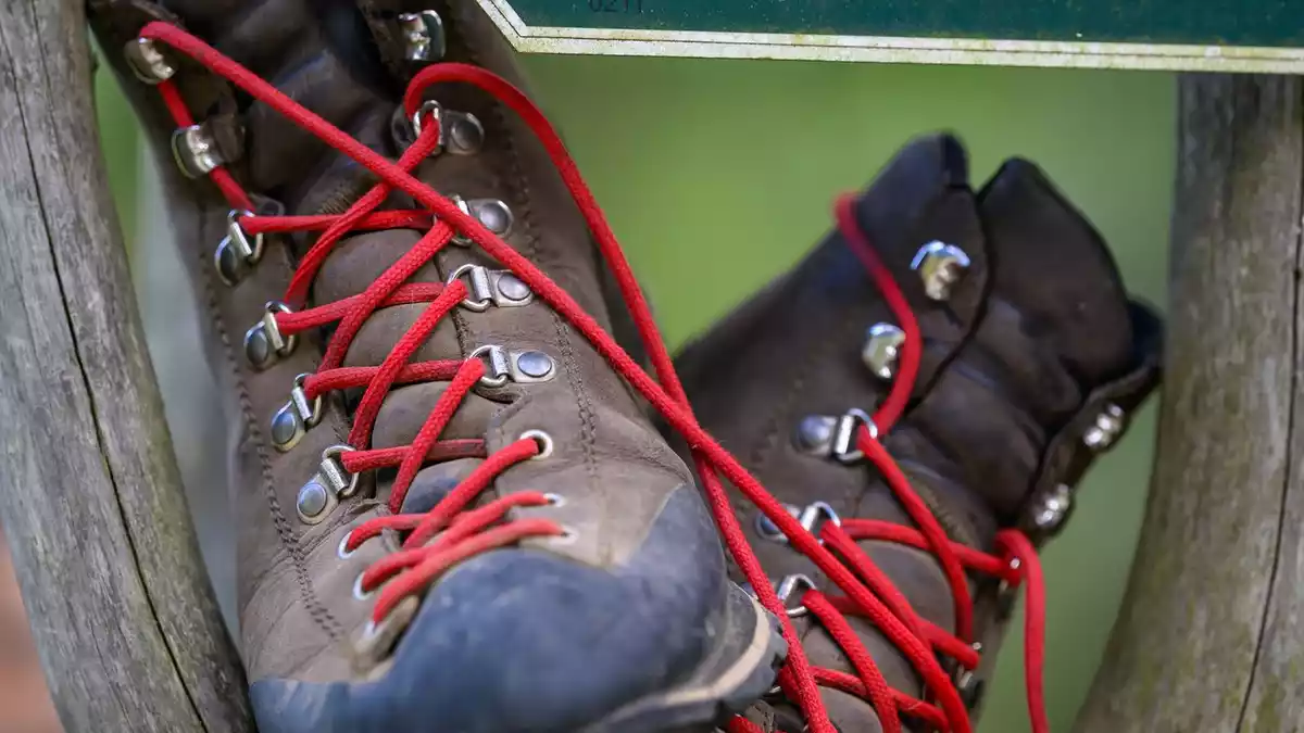 Wanderschuhe stehen in einem Wegweiser am Fuß des Fichtelbergs. - Bild: Hendrik Schmidt/dpa
