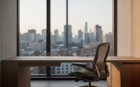 Ein minimalistischer, moderner Arbeitsbereich mit einem leeren Schreibtisch vor einem hellen Fenster. - Foto: über boerse-global.de