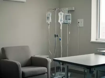 Ein steriler, hell beleuchteter Behandlungsraum in einer Klinik mit einem Infusionsständer und einem bequemen Sessel. - Foto: über boerse-global.de