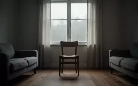 Ein minimalistisch eingerichtetes Wohnzimmer im frühen Morgenlicht mit einem leeren Stuhl vor einem Fenster. - Foto: über boerse-global.de