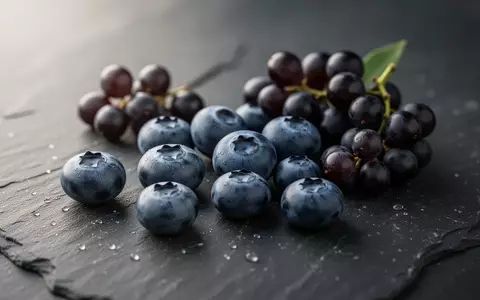 Frische Blaubeeren und Weintrauben liegen auf einem dunklen Steinhintergrund. - Foto: über boerse-global.de