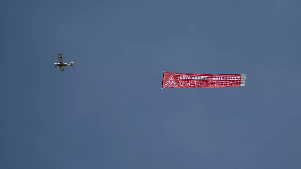 Ein Flugzeug mit einem IG-Metall-Banner fliegt über das Porsche-Stammwerk in Zuffenhausen. - Bild: Marijan Murat/dpa