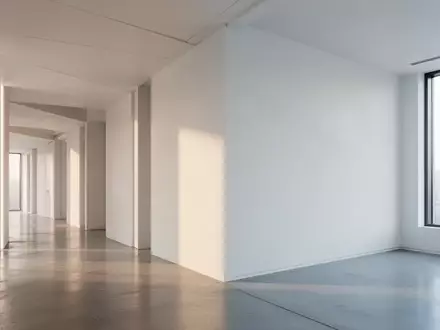 Ein minimalistischer, leerer Büroflur mit klaren architektonischen Linien und natürlichem Lichteinfall. - Foto: über boerse-global.de
