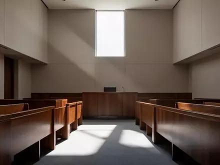 Ein minimalistischer, leerer Gerichtssaal mit polierten Holzbänken und hellem Lichteinfall durch hohe Fenster. - Foto: über boerse-global.de