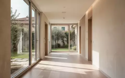 Ein lichtdurchfluteter, minimalistischer Flur in einer modernen italienischen Gesundheitseinrichtung mit Blick in einen Garten. - Foto: über boerse-global.de
