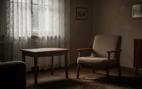 Ein ruhiges, spärlich eingerichtetes Wohnzimmer mit einem leeren Sessel und einem Holztisch bei gedämpftem Tageslicht. - Foto: über boerse-global.de