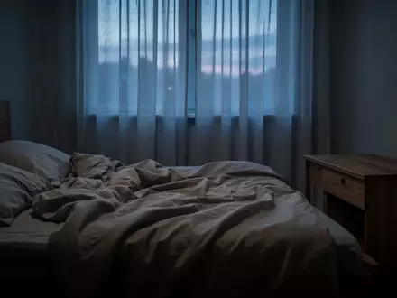 Ein ungemachtes Bett in einem ruhig beleuchteten Schlafzimmer bei Dämmerung, das eine Atmosphäre von Erschöpfung und Stille vermittelt. - Foto: über boerse-global.de