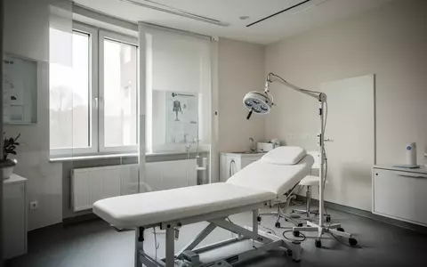 Ein leerer, modern eingerichteter Behandlungsraum in einer Arztpraxis mit einer Untersuchungsliege und hellem Tageslicht. - Foto: über boerse-global.de