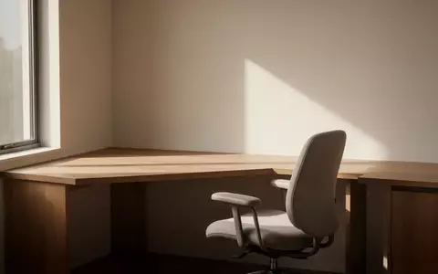 Ein minimalistisch eingerichteter, heller Arbeitsplatz mit einem Holztisch und einem ergonomischen Stuhl. - Foto: über boerse-global.de