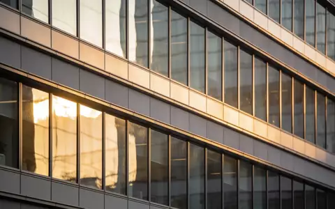 Moderne Glasfassade eines Bürogebäudes im Finanzviertel bei Sonnenuntergang. - Foto: über boerse-global.de
