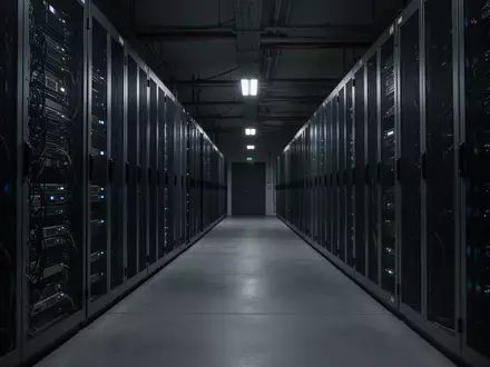Ein dunkler, moderner Serverraum mit leuchtenden LED-Anzeigen an metallischen Serverschränken. - Foto: über boerse-global.de