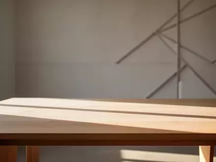 Ein minimalistischer, sonnendurchfluteter Arbeitsplatz mit einem leeren Holztisch und weichem, natürlichem Licht. - Foto: über boerse-global.de