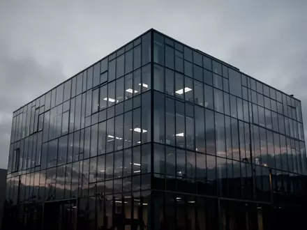 Ein modernes, minimalistisches Bürogebäude in der Dämmerung, das die zunehmende Unsicherheit in der Führungsebene symbolisiert. - Foto: über boerse-global.de