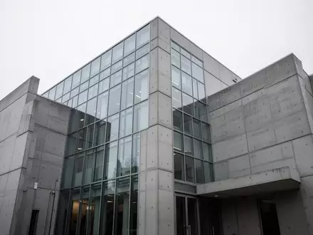 Moderne, minimalistische Fassade eines Gerichtsgebäudes aus Glas und Beton unter bewölktem Himmel. - Foto: über boerse-global.de