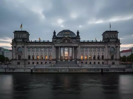 Das Reichstagsgebäude in Berlin in der Abenddämmerung bei bewölktem Himmel. - Foto: über boerse-global.de