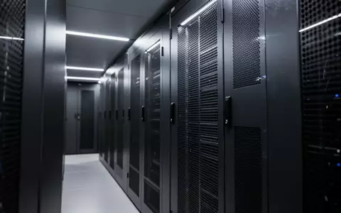 Moderne, minimalistische Serverraum-Architektur mit dunklen Metallschränken und dezenter Beleuchtung. - Foto: über boerse-global.de