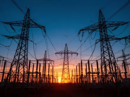 Ein großes Umspannwerk mit Hochspannungsmasten in der Dämmerung, das den massiven Energiebedarf der digitalen Industrie versinnbildlicht. - Foto: über boerse-global.de