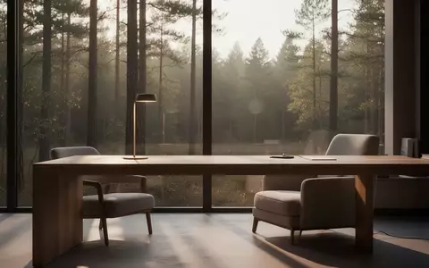 Ein minimalistischer Arbeitsbereich mit einem leeren Schreibtisch und einer Schreibtischlampe vor einem Fenster mit Waldblick. - Foto: über boerse-global.de