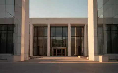 Eine moderne, minimalistische Steinfassade eines Regierungsgebäudes bei Sonnenuntergang. - Foto: über boerse-global.de