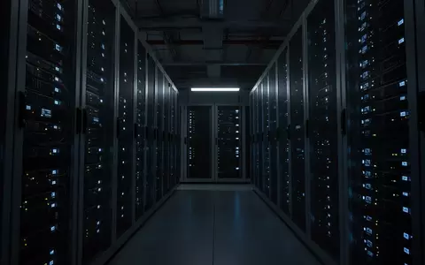 Dunkler, moderner Serverraum mit blauen Status-LEDs an metallischen Serverschränken, der die technologische Infrastruktur symbolisiert. - Foto: über boerse-global.de