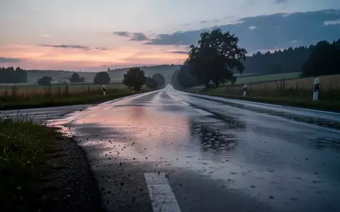 Eine leere, regennasse Landstraße in der Dämmerung, die eine nachdenkliche Atmosphäre für die Debatte um Verkehrssicherheit schafft. - Foto: über boerse-global.de