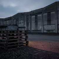 Ein verlassenes Industriegebäude bei Dämmerung mit leeren Holzpaletten auf einem Kiesplatz. - Foto: über boerse-global.de