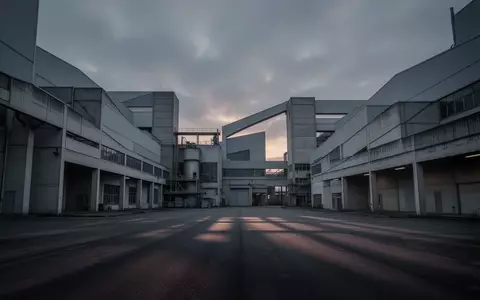 Weitläufiges, modernes Fabrikgebäude bei Dämmerung unter einem bewölkten Himmel, das die industrielle Atmosphäre verdeutlicht. - Foto: über boerse-global.de