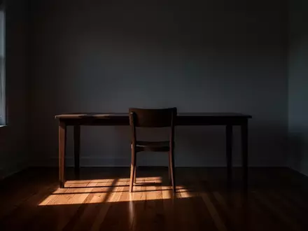 Ein leerer Arbeitsplatz in einem minimalistischen Raum mit langen Schatten bei Dämmerung, der eine Atmosphäre von Isolation und Ruhe vermittelt. - Foto: über boerse-global.de