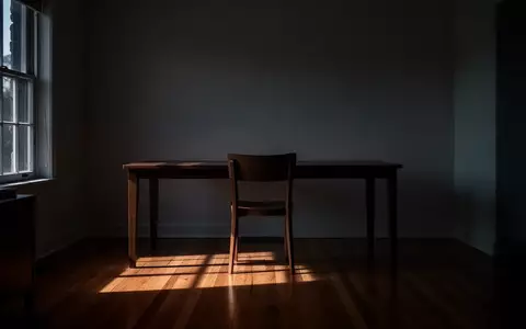 Ein leerer Arbeitsplatz in einem minimalistischen Raum mit langen Schatten bei Dämmerung, der eine Atmosphäre von Isolation und Ruhe vermittelt. - Foto: über boerse-global.de
