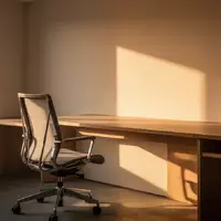 Ein minimalistisch eingerichtetes Homeoffice mit einem leeren Schreibtisch und einem ergonomischen Stuhl im Sonnenlicht. - Foto: über boerse-global.de