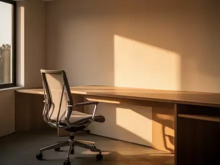 Ein minimalistisch eingerichtetes Homeoffice mit einem leeren Schreibtisch und einem ergonomischen Stuhl im Sonnenlicht. - Foto: über boerse-global.de