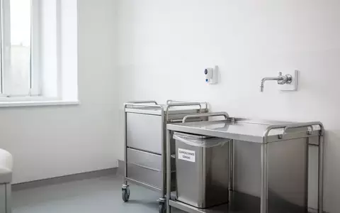 Ein minimalistisch eingerichteter, heller Behandlungsraum in einer Kinderarztpraxis mit einem medizinischen Wagen. - Foto: ĂĽber boerse-global.de