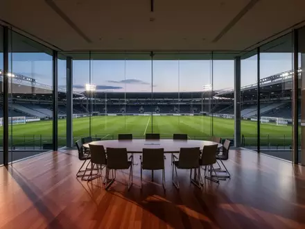 Ein leerer, moderner Sitzungssaal mit Blick auf ein Fußballstadion in der Abenddämmerung. - Foto: über boerse-global.de