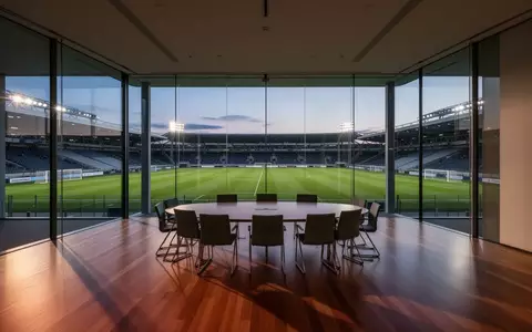 Ein leerer, moderner Sitzungssaal mit Blick auf ein Fußballstadion in der Abenddämmerung. - Foto: über boerse-global.de