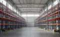 Leere Lagerhalle mit hohen Regalsystemen und moderner Industriearchitektur als Symbol für Warenlogistik und Nachhaltigkeit. - Foto: über boerse-global.de