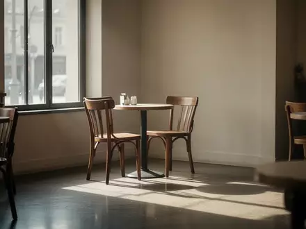 Ein einsamer Stuhl an einem kleinen runden Tisch in einem leeren, lichtdurchfluteten Café. - Foto: über boerse-global.de