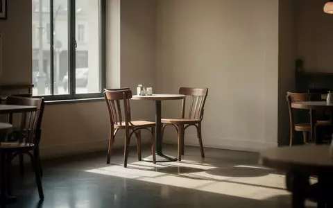 Ein einsamer Stuhl an einem kleinen runden Tisch in einem leeren, lichtdurchfluteten Café. - Foto: über boerse-global.de