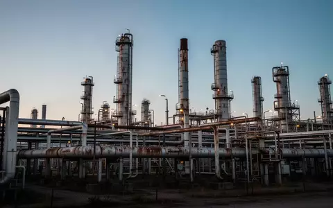 Industrielle Ölraffinerie bei Dämmerung mit komplexen Rohrleitungen und Destillationsanlagen vor einem klaren Abendhimmel. - Foto: über boerse-global.de