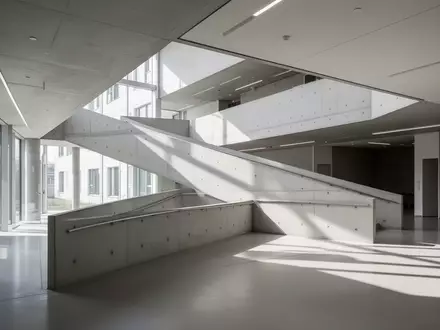 Eine moderne, minimalistische Betonrampe in einem hellen, zeitgenössischen Gebäudeinneren. - Foto: über boerse-global.de