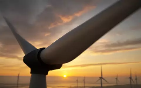 Moderne Windkraftanlage vor einem goldenen Abendhimmel im Licht der untergehenden Sonne - Foto: über boerse-global.de