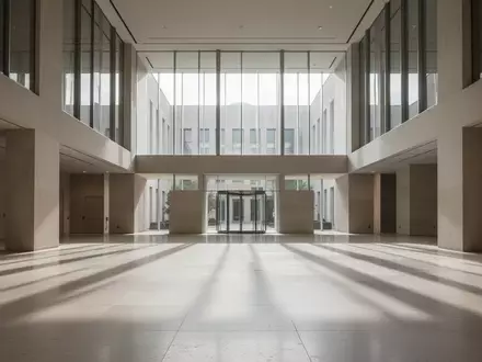 Ein minimalistisches, menschenleeres Atrium eines modernen Verwaltungsgebäudes mit klaren Linien und natürlichem Lichteinfall. - Foto: über boerse-global.de