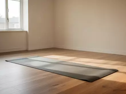 Ein heller, minimalistischer Übungsraum mit einer leeren Yogamatte auf einem Holzboden, durchflutet von natürlichem Tageslicht. - Foto: über boerse-global.de