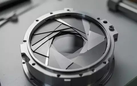 Nahaufnahme einer hochpräzisen mechanischen Blendenmechanik mit überlappenden Lamellen auf einer Werkbank. - Foto: über boerse-global.de