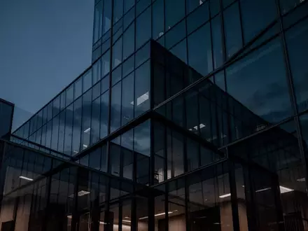Moderne, minimalistische Glasfassade eines Bürogebäudes in der Dämmerung, die eine sichere und undurchdringliche Umgebung symbolisiert. - Foto: über boerse-global.de